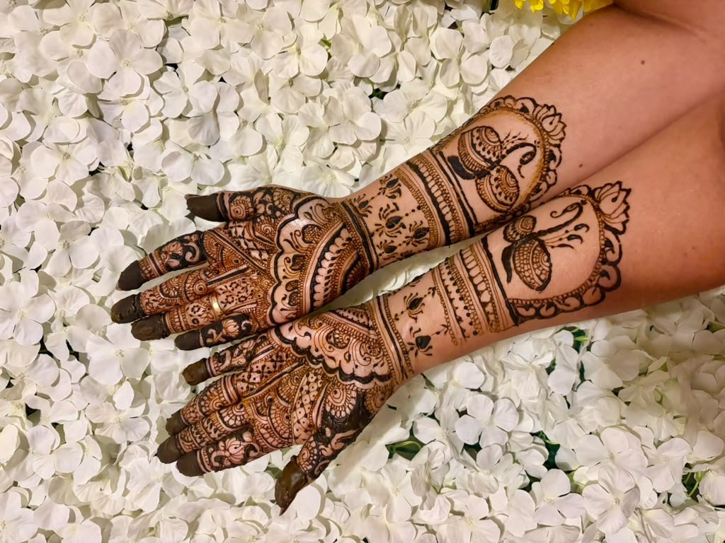 Farhat’s bridal henna with peacock motifs on hands resting over white petals